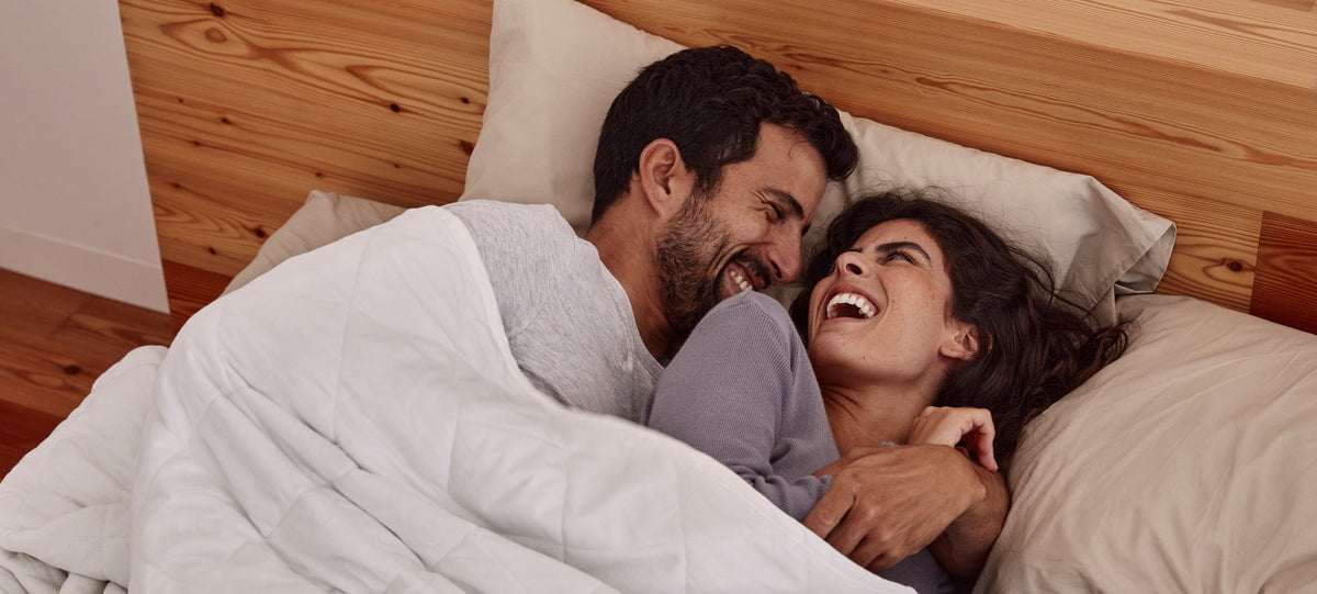 Pareja despertando feliz bajo la blanky